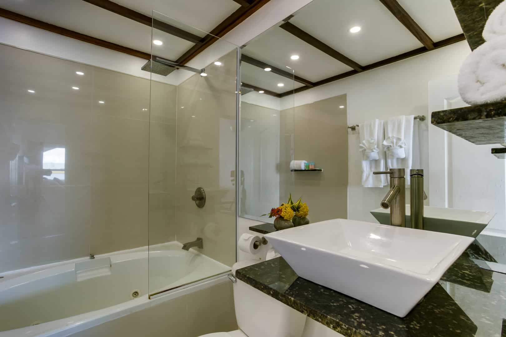 The master bathroom with a large vanity mirror, marble counter, ceramic sink and a walk in shower with a tub inside the 2 Bedroom Lagoon Bayview at Umaya Resort & Adventure